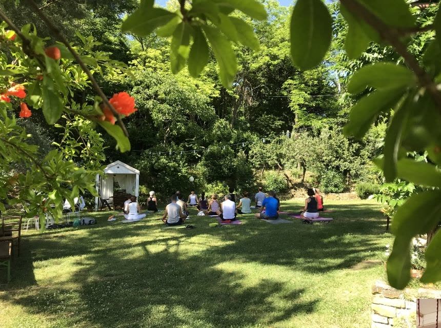 Lezione di yoga all'aperto in un giardino, tra gli alberi